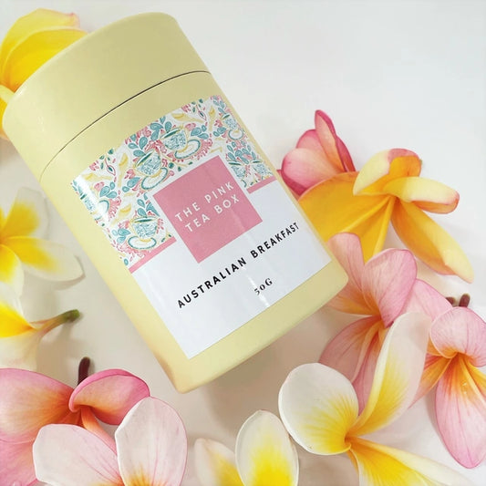 pretty lemon colour tea canister containing Australian Breakfast tea from The Pink Tea Box, surrounded by frangipini flowers