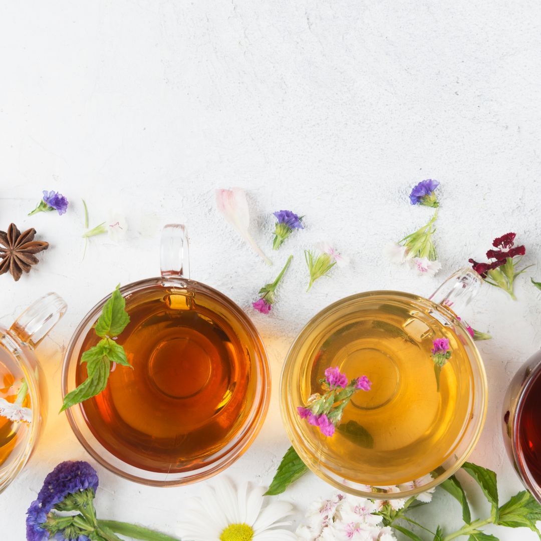 glass cups with a selection of healthy teas with flower petals scattered around the cups